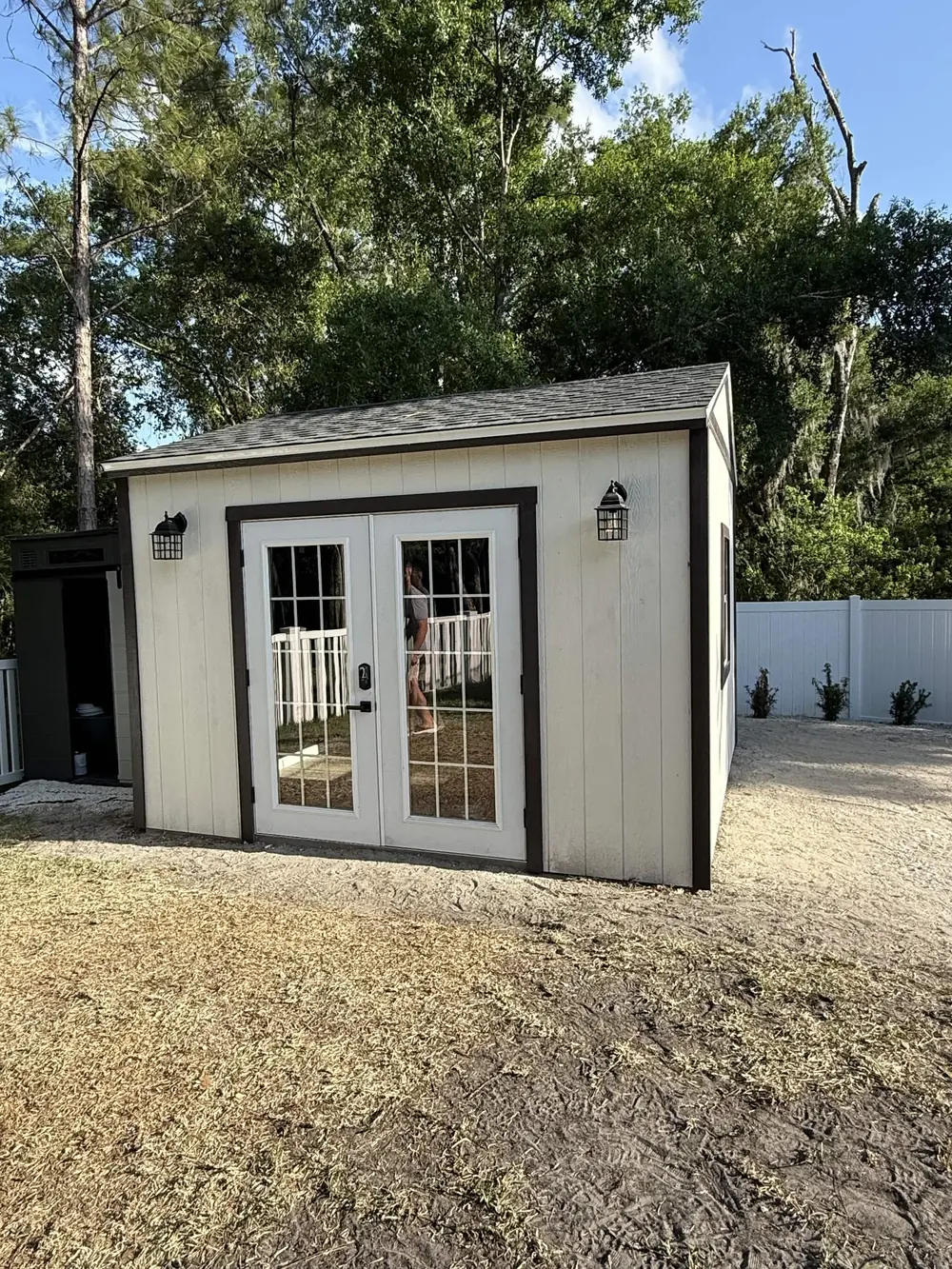 White custom studio shed with glass double doors and exterior lights