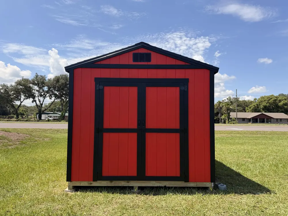 Red barn-style storage shed with black trim and double doors