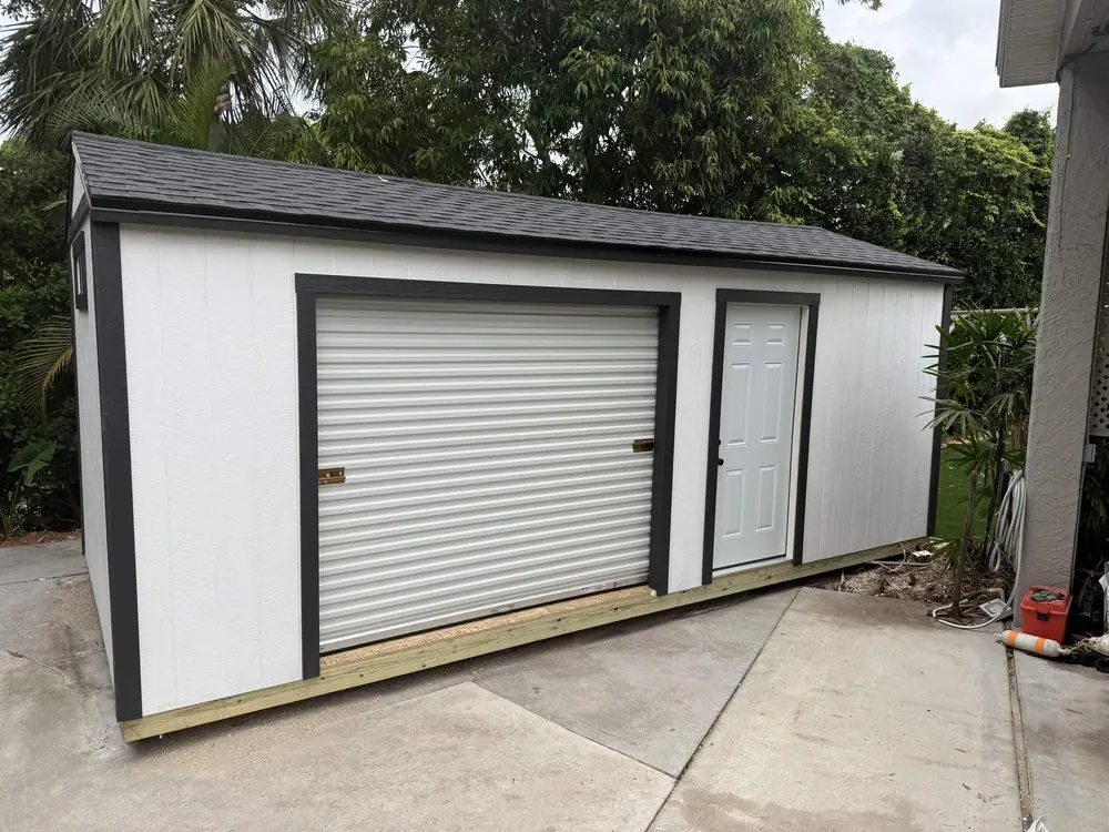 Black and white workshop shed with a roll-up garage door